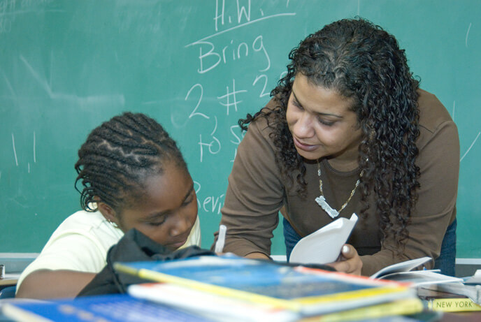 Teacher helping student in front of chalkboard