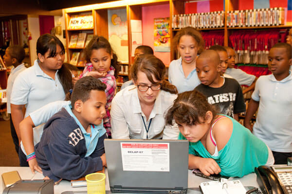 Teacher at computer surrounded by students