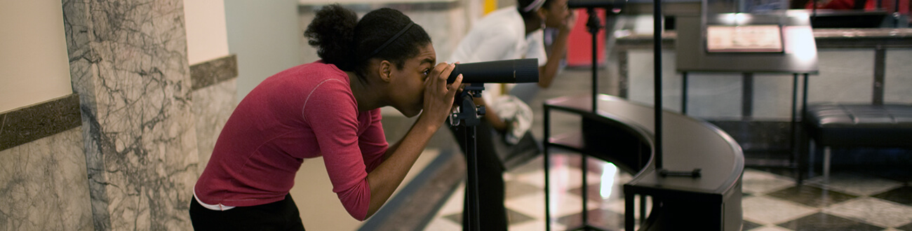 Girl with telescope at museum